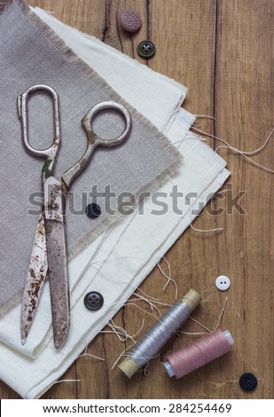 Vintage Background with sewing tools and colored tape Sewing kit. Scissors, bobbins with thread and needles on the old wooden background
