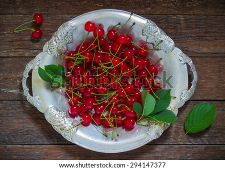 cherries in a metallic plate on a wooden background