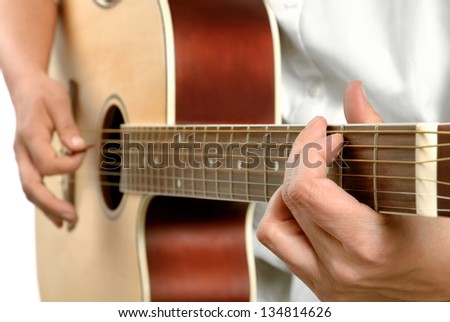 Female guitar player\'s hands playing on an acoustic guitar, white shirt and background