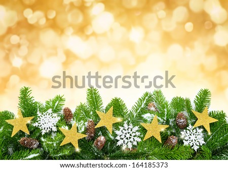 Studio shot of fir twigs decorated with stars, snow and cones on blurred lights background