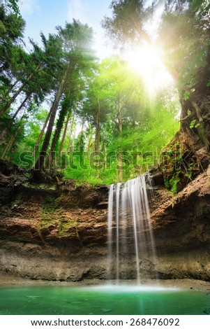 Fascinating wide-angle landscape shot of a paradise with waterfalls on multi-layered cliffs, fresh green forest, blue sky and the sun shining bright