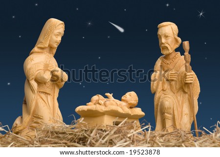 Wooden figures of Mary and Joseph watching baby Jesus, with night sky and comet