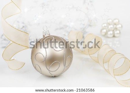 Christmas ornament on slightly reflecting surface, light colors, background out of focus