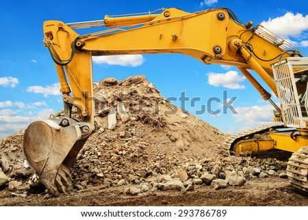 Yellow excavator and a heap of dirt, in the background a nice blue sky with white clouds