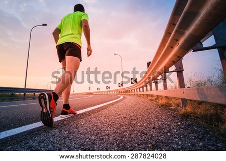 Man running on a paved road at the sunset