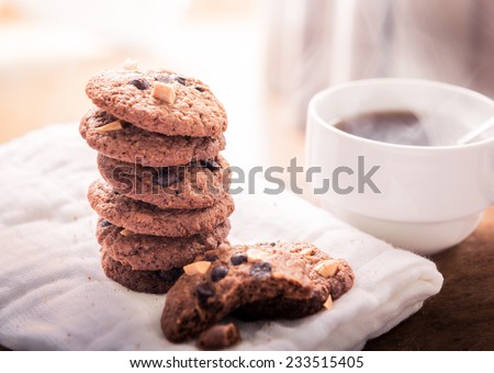 Chocolate chip cookies on napkin and hot tea on wooden table. Stacked chocolate chip cookies close up
