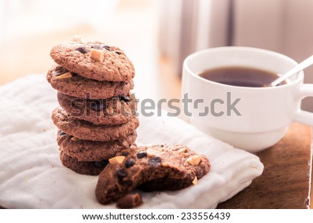 Chocolate chip cookies on napkin and hot tea on wooden table. Stacked chocolate chip cookies close up