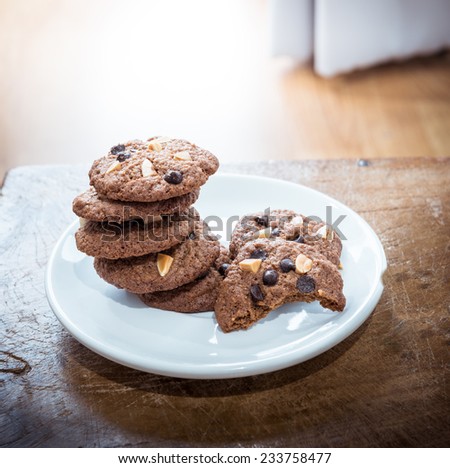 Chocolate chip cookies in white dish on wooden table. Stacked chocolate chip cookies close up