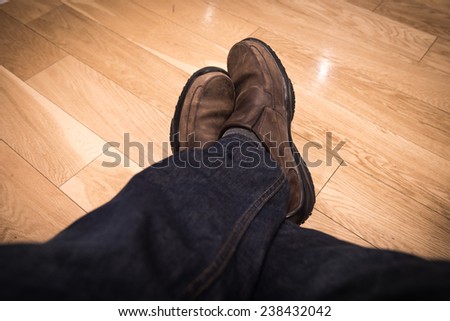 closeup male seat and legs in shoes on the wooden floor