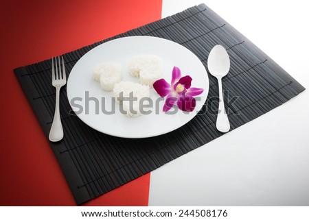 cooked rice heart shapes with a spoon and fork on white dish  in Platemat and on half of red and white background
