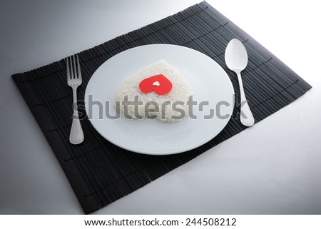 cooked rice heart shapes with a spoon and fork on white dish  in Platemat and on white background