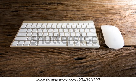 Wireless computer keyboard with the English and Thai alphabet and mouse on wooden table