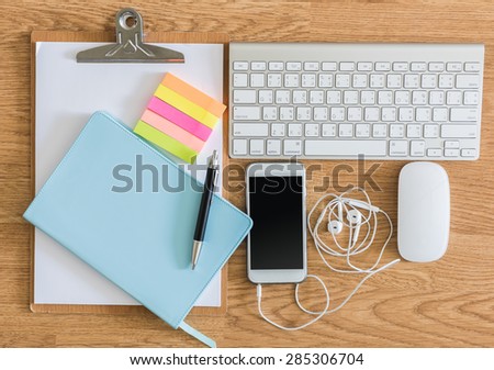 overhead of office table with clipboard, notepad, computer keyboard and mouse, pen and smartphone. copy space
