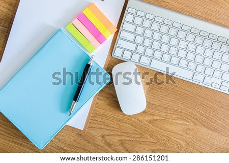 overhead of office table with clipboard, notepad, computer keyboard and mouse, pen and smartphone. copy space