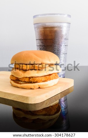 chicken hamburger and glass of cola, wooden cutting board with reflections