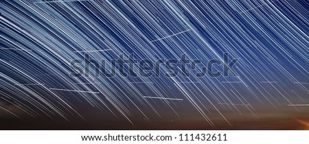 Extreme long exposure image showing star trails and aircraft trails in the night sky