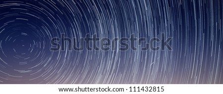 Two shooting stars streak across a long exposure star trail revolving around Polaris or the Northern Star