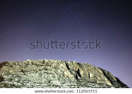 A shooting star streaks across the sky over the GHar Lapsi cliff face in Malta