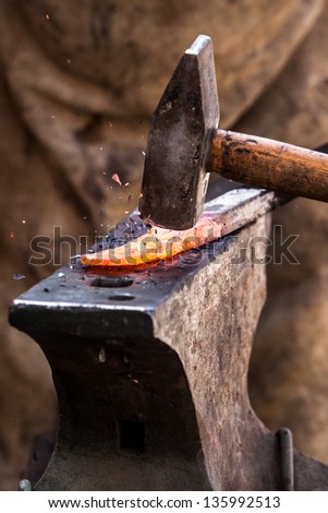 Blacksmith working on metal on anvil at forge detail shot