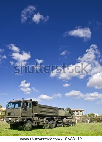Large logistics support military truck with mechanical shovel in tow