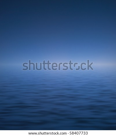 Venus emerging in a deep blue sky over calm ocean waters