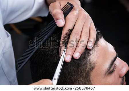 Professional hairdresser is cutting men\'s hair in beauty salon.