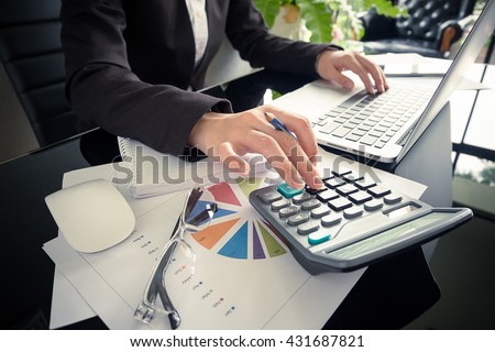 Business woman using a calculator to calculate the numbers on his desk in a office.