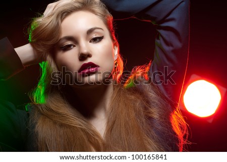 Beautiful girl posing in front of shining colored creative lighting background