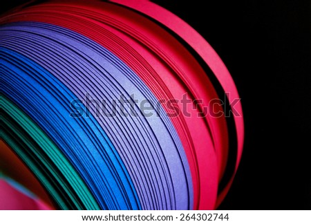 Green,blue,purple and magenta paper strips over black background