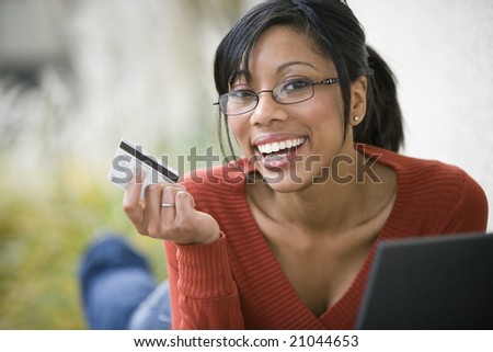 Smiling African American woman shopping on-line with credit card and laptop
