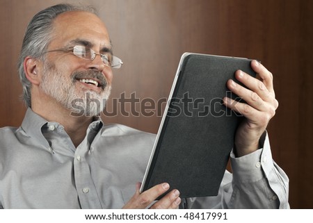 Portrait of a smiling businessman reading information from an electronic tablet. Horizontal shot.