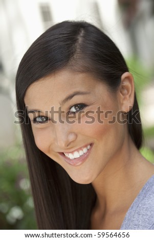 Portrait of a beautiful Asian woman smiling into the camera in an outdoor setting. Vertical shot.