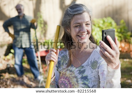 Mature couple doing yard work and on the cell phone