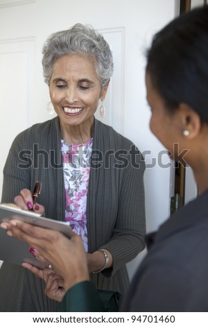 Black senior woman signs a petition at her front door