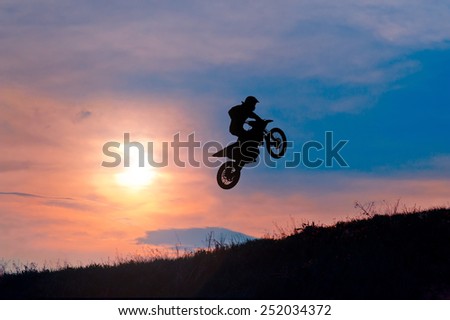 Extreme sports background - silhouette of biker jumping on motorbike on sunset