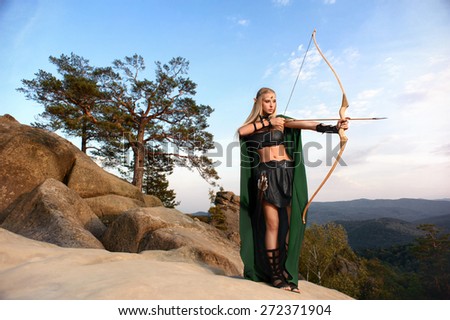 Woman elf warrior in the mountains against the sky the bow