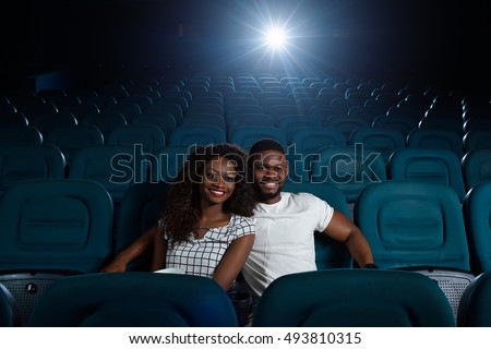 Whole cinema to ourselves. Shot of a joyful young beautiful African couple in love watching a movie in an empty cinema auditorium copyspace