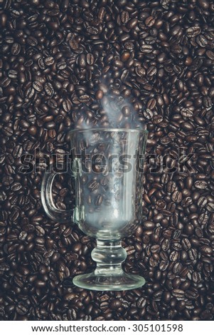 Irish coffee glass stuck in fresh coffee beans. Smoke is coming out of the glass.