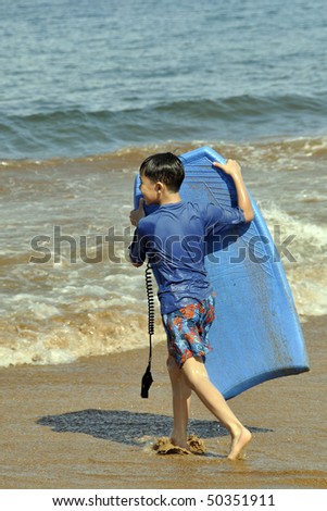 An Asian Child carrying a boogie board