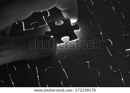Hand lays black puzzle on a white background