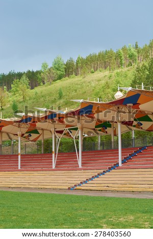 Covered outdoor arena for spectators with wooden seats