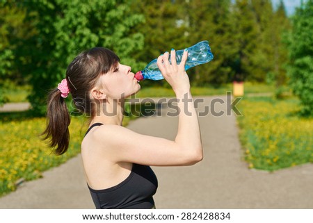 Girl after workout drink water from plastic bottles