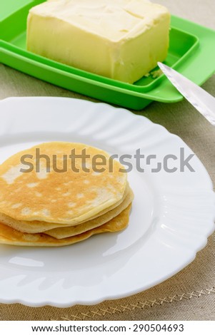On a white plate stack of pancakes and butter