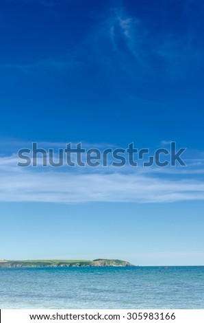 Brilliant blue sky and ocean water in dramatic vertical composition features Gribbin Head (Cornwall, United Kingdom).