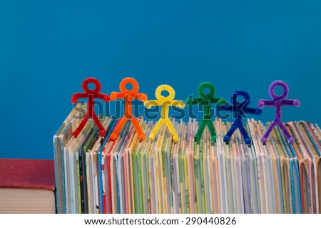 Rainbow colors in pipe-cleaner people. The people/children are all lined up on a pile of books. This is a great photo to help teach educational ideas and concepts to people around the world.