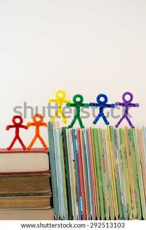Rainbow colors in pipe-cleaner people. The people/children are all lined up on a pile of books. This is a great photo to help teach educational ideas and concepts to people around the world.