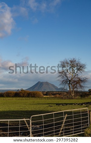 A late-afternoon, winter view of Mount Edgecumbe, a volcano in the Bay of Plenty, New Zealand. The stretch of farmland and the dramatic sky is a feast to bold. Good for greeting cards and other ideas.