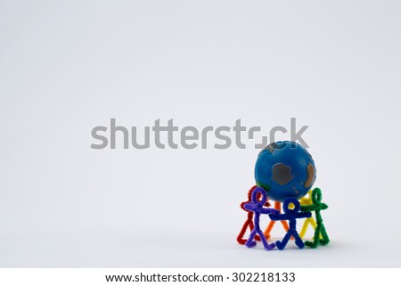 A group of rainbow pipe-cleaner people holding the world. They are working together to make a more peaceful world or to fix the world. This could be used for many ideas and concepts around the world.