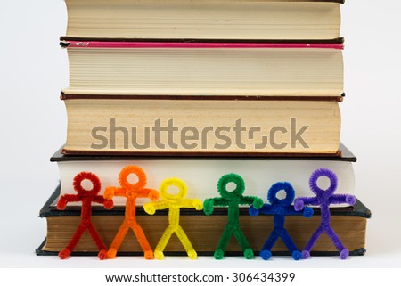 A line of rainbow pipe-cleaner people with a pile of antique books. They want to promote educational, multicultural, and international ideas and concepts to people and children around the world.