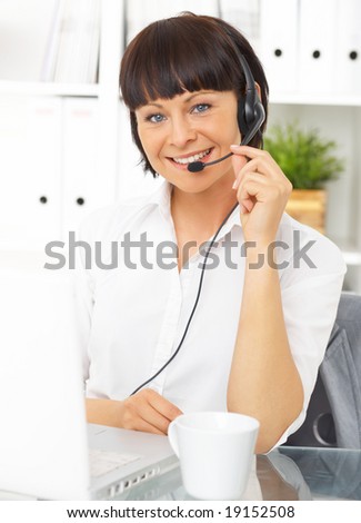 Beautiful secretary with headset is working in office